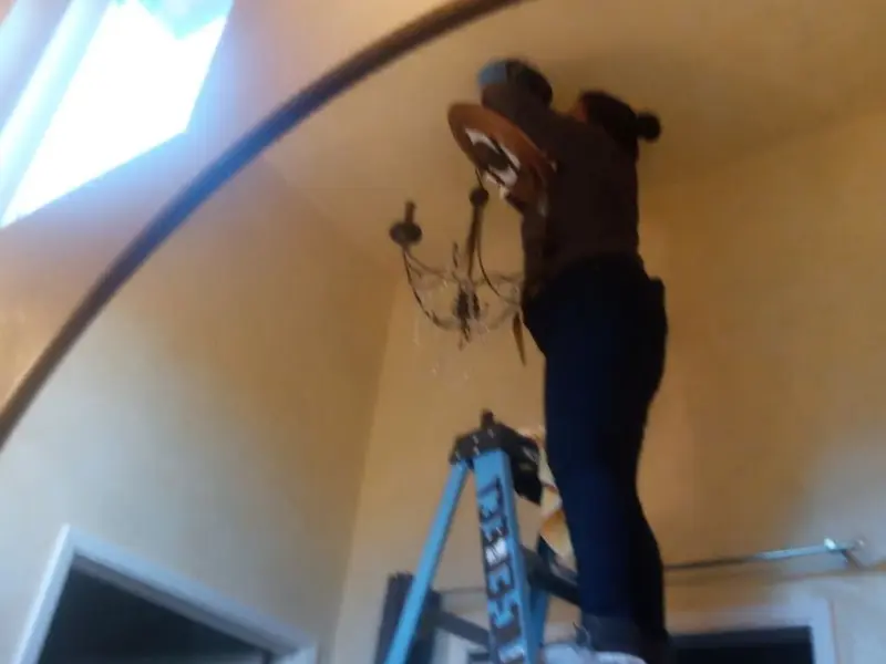 Electrician installing a chandelier in a Durango residence